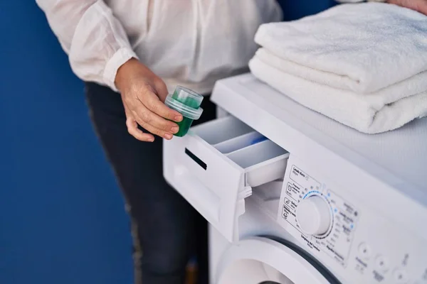 洗衣房的洗衣机上倒洗涤剂的中年妇女 — 图库照片