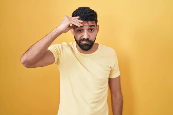 額に手で問題について心配し 強調し 黄色の背景の上に立って髭を持つヒスパニック系の男 危機への神経と不安 — ストック写真
