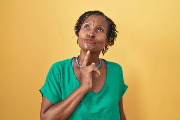 Afrikaanse Vrouw Met Dreadlocks Staan Gele Achtergrond Denken Geconcentreerd Twijfel — Stockfoto