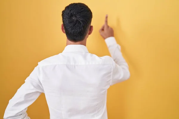 Young Hispanic Man Standing Yellow Background Posing Backwards Pointing Ahead — Stockfoto