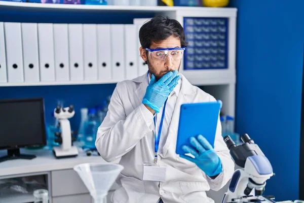 Handsome Latin Man Working Scientist Laboratory Using Tablet Covering Mouth — Stock Photo, Image
