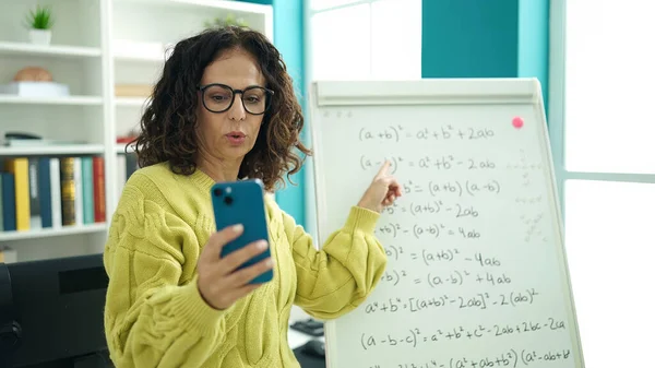 Middle age hispanic woman teacher explaining online maths exercise at library university