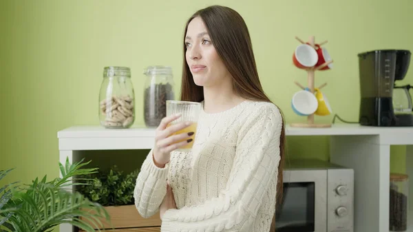 年轻美丽的惊慌失措的女人举着一杯橙汁站在家里 — 图库照片