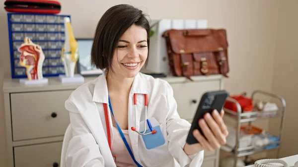 Mujer Joven Caucásica Médico Sonriendo Videollamada Con Teléfono Inteligente Clínica —  Fotos de Stock