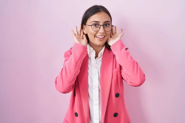 若いヒスパニック系の女性は ビジネス服や眼鏡を耳のジェスチャーで両方の手を聞くしようとすると ゴシップを好奇心を着て 聴覚障害や聴覚障害 — ストック写真