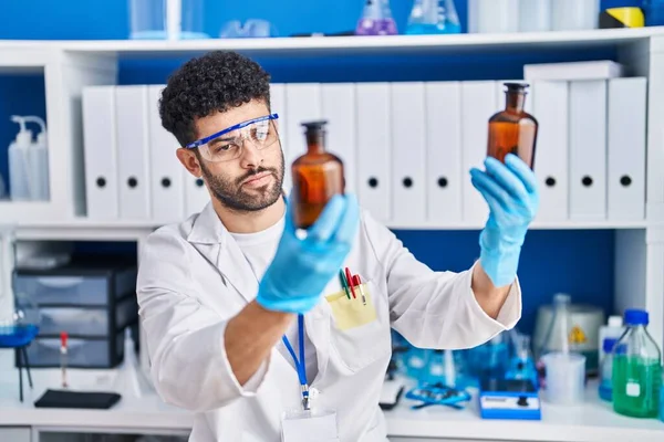 Giovane Arabo Che Indossa Uniforme Scienziato Che Tiene Bottiglie Laboratorio — Foto Stock