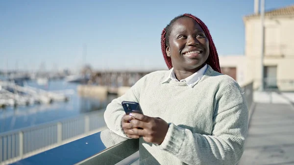 海辺でスマートフォンを使用して編組髪アフリカの女性 — ストック写真