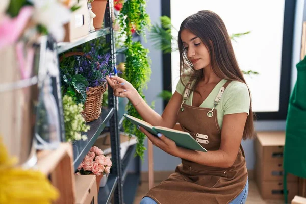 Joven Hermosa Mujer Hispana Florista Leyendo Cuaderno Tocando Planta Tienda —  Fotos de Stock