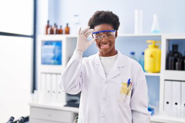 African american woman wearing scientist uniform standing at laboratory