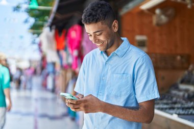 Afro-Amerikan bir adam, markette akıllı telefon kullanarak kendinden emin gülümsüyor.