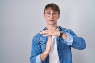 Beyaz, sarışın, gözlüklü bir adam. El kol hareketi yapıyor. Hayal kırıklığına uğramış ve ciddi bir yüz ifadesi var. 