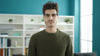 Kütüphanede rahat bir ifadeyle duran genç İspanyol öğrenci.