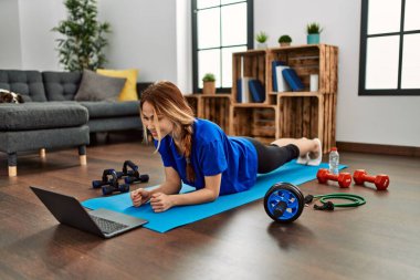 Genç beyaz kadın gülümsüyor evde özgüven egzersizi yapıyor.