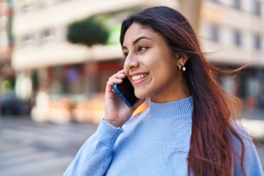 Genç İspanyol kadın gülümsüyor. Kendine güveniyor. Akıllı telefondan konuşuyor.