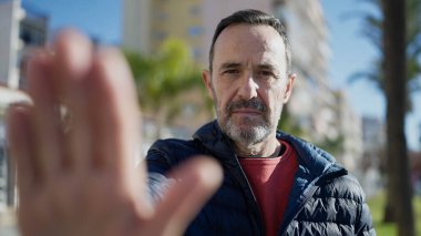 Middle age man doing stop gesture with hand at street