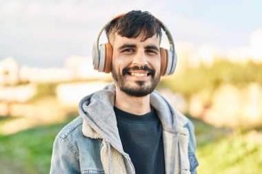 Young hispanic man smiling confident listening to music at park