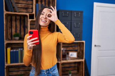 Akıllı telefon kullanan genç esmer kadın gülümsüyor. Mutluluktan gülümsüyor. 