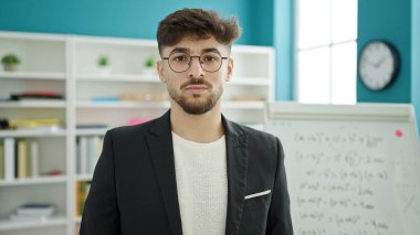 Üniversite sınıfında rahat bir ifadeyle duran genç Arap erkek öğrenci.