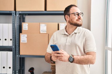 Ofiste akıllı telefon kullanan Latin asıllı genç bir e-ticaret işçisi.
