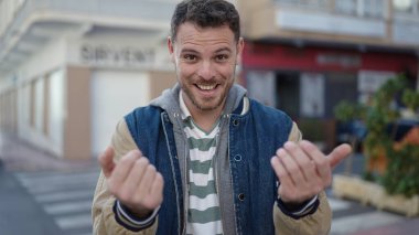 Beyaz bir adam gülümsüyor. Kendine güveniyor. Caddeye gelmek istiyor.