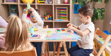 Anaokulunda kağıt kesme oyunu oynayan sevimli kızlar ve oğlanlar.