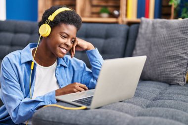 Evde dizüstü bilgisayar kullanan Afrikalı Amerikalı bir kadın.