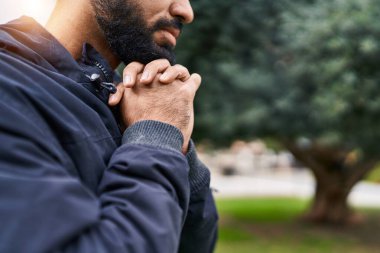 Genç İspanyol adam parkta gözleri kapalı dua ediyor.