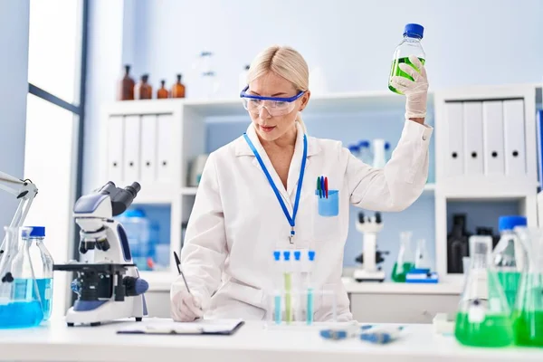 Young Blonde Woman Wearing Scientist Uniform Holding Bottle Laboratory — Stock fotografie