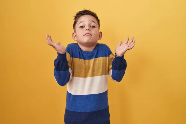 黄色の背景に叫んで大声で側に手を口に大声で叫んで立っている小さなヒスパニック系の少年 コミュニケーションの概念 — ストック写真