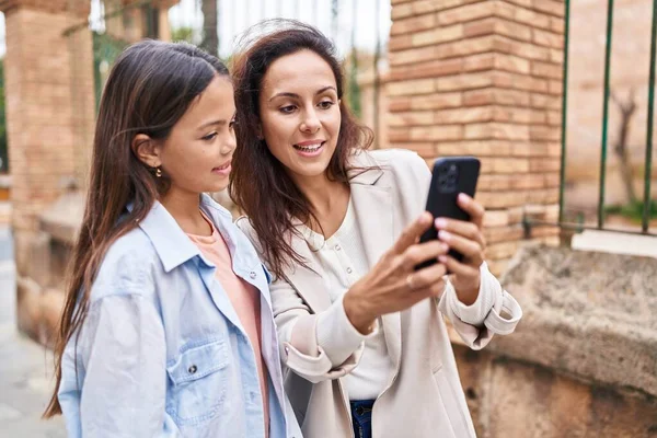 女性と少女の母親と娘が路上でスマートフォンを使って — ストック写真