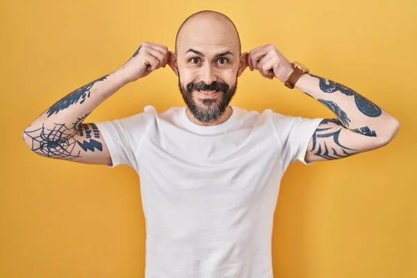 Jonge Spaanse Man Met Tatoeages Gele Achtergrond Lachende Trekkende Oren — Stockfoto