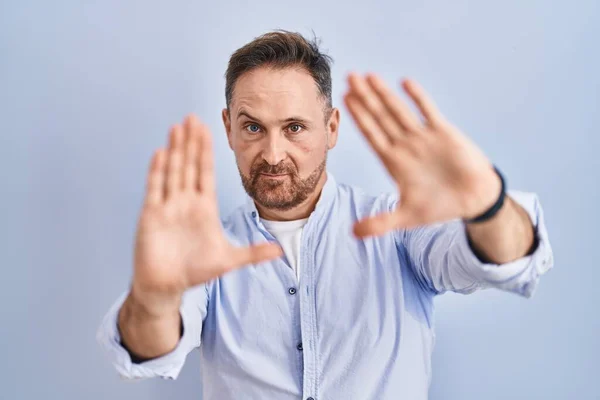 Orta Yaşlı Beyaz Bir Adam Mavi Arka Planda Duruyor Parmaklarıyla — Stok fotoğraf
