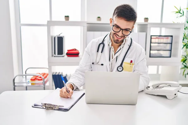 Young Hispanic Man Doctor Using Laptop Writing Medical Report Clinic — Stock Photo, Image
