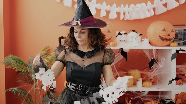 Middle Age Hispanic Woman Holding Skull Decoration Having Halloween Party – stockfoto