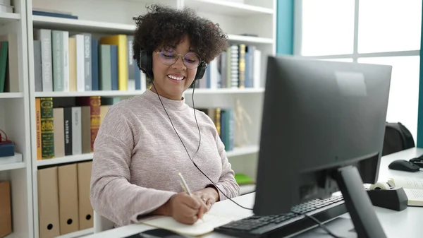 アフリカ系アメリカ人の若い女性が大学の教室でノートにコンピュータライティングを使って — ストック写真