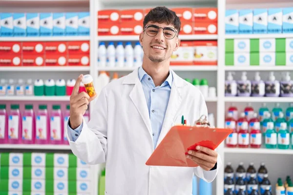Jovem Hispânico Homem Farmacêutico Segurando Pílulas Garrafa Leitura Documento Farmácia — Fotografia de Stock
