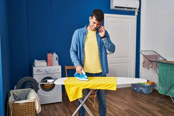 Genç Spanyol Adam Akıllı Telefonda Konuşuyor Çamaşırhanede Giysileri Ütülüyor — Stok fotoğraf