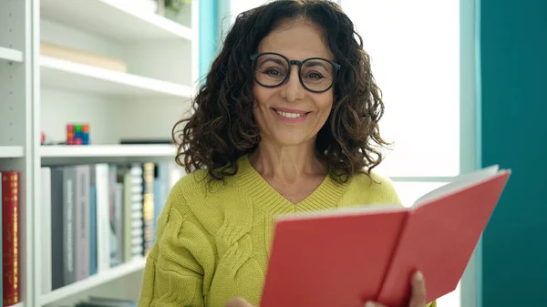 Middle Age Hispanic Woman Teacher Smiling Confident Reading Book Library — Stock Photo, Image