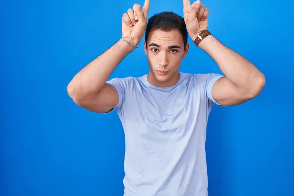 Mladý Hispánec Muž Stojící Nad Modrým Pozadím Dělá Legrační Gesto — Stock fotografie