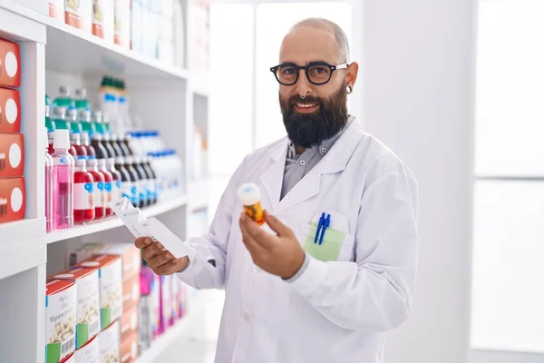 Young Bald Man Pharmacist Holding Pills Bottle Reading Prescription Pharmacy — Foto Stock