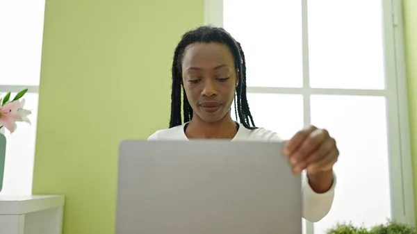 アフリカ系アメリカ人の女性がノートパソコンを使って家のテーブルに座り — ストック写真