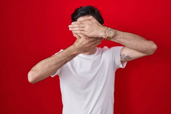 Kırmızı Arka Planda Duran Genç Spanyol Adam Gözlerini Ağzını Elleriyle — Stok fotoğraf