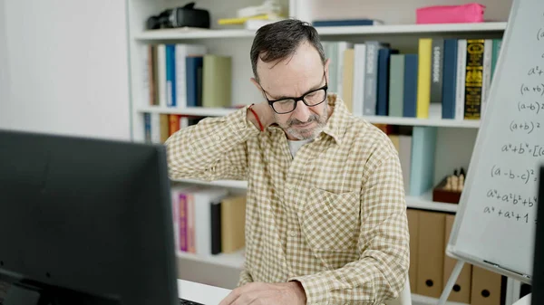 Middle age man teacher working stressed at classroom