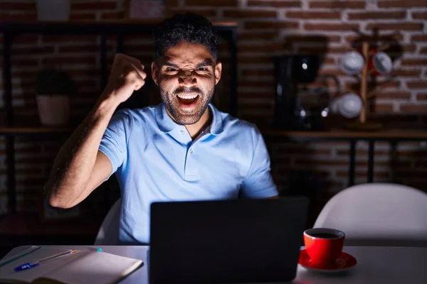 Латиноамериканец Бородой Использует Ноутбук Ночью Злой Безумный Поднимающий Кулак Расстроенный — стоковое фото