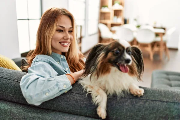 Young caucasian woman smiling confident sitting on sofa with dog at home
