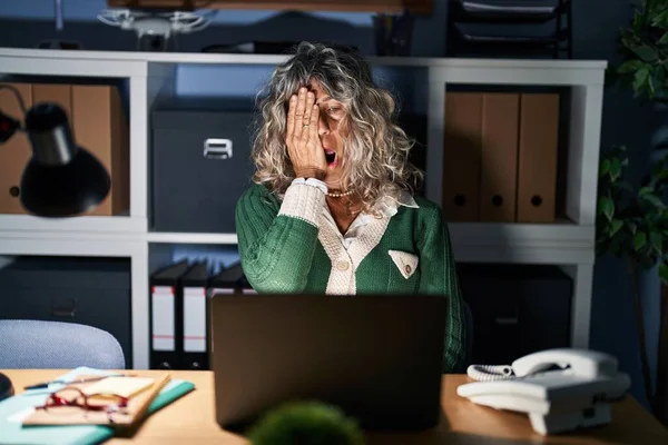 コンピュータのラップトップを使用して夜に働いている中年の女性は 半分の顔 口を手で覆い疲れてあくびをしています 痛みで顔が痛い — ストック写真