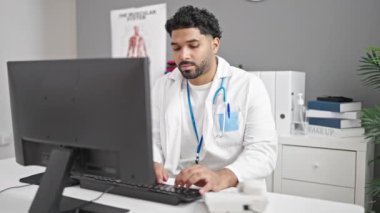 Afrikalı Amerikalı doktor klinikte telefonla konuşan bilgisayar kullanıyor.