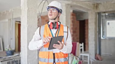 Kafkasyalı genç bir mimar inşaat alanında dokunmatik ped kullanarak rahat bir ifadeyle ayakta duruyor.