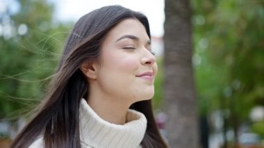 Young beautiful hispanic woman breathing with closed eyes at park