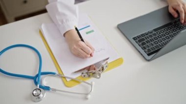 Genç, güzel İspanyol kadın doktor klinikteki panoda dizüstü bilgisayar kullanıyor.